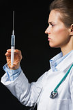 Doctor woman with syringe on black background