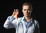 Doctor woman showing test tube on black background