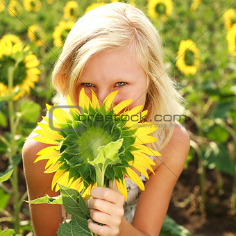 Young blonde girl playing with sunflower