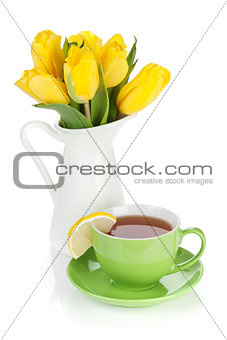 Yellow tulips and tea cup with lemon slice