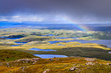 Scenic view of beautiful lakes, clouds and rainbow in Inverpolly