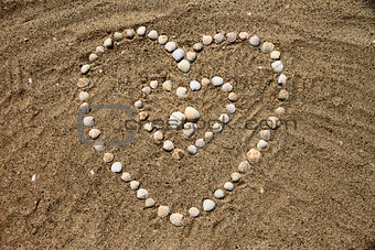 Seashells on the sand in the form of heart
