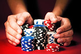 Man's hands move the winnings casino chips on red table.