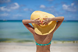 Woman sitting on beach holding hat