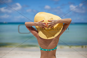 Woman sitting on beach holding hat