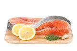 Salmon steaks on cutting board with lemons and herbs