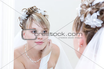 young bride looks into a big mirror