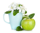 Ripe green apples and flowers in cup
