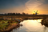 windmill during sunrise reflected in river