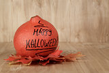 Happy Halloween inscription on the pumpkin with leaves
