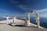 The newlyweds pose near the wedding arch in the mountains against the blue sky