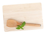 Cooking utensil and basil leaves over cutting board