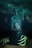 Glass bell jar with crow and skeleton hands