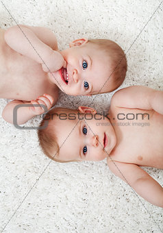 Twin babies laying on the floor