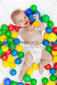 Happy baby boy with lots of colorful balls