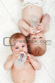 Babies drinking water from feeding bottles