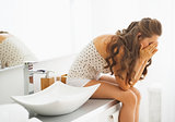 Stressed young woman sitting in bathroom