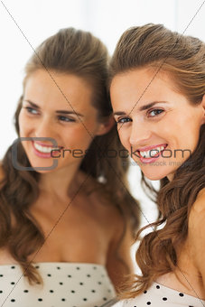 Portrait of smiling young woman with reflection in the mirror