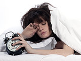 woman in bed awakening tired holding alarm clock