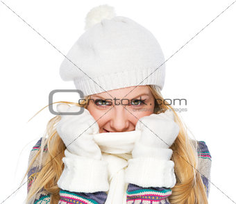 Happy girl in winter clothes hiding in scarf
