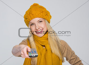 Happy girl in scarf and hat with tv remote control isolated on g