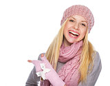 Happy girl in winter clothes pointing on copy space