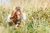 Girl is writing sms on the phone lying in grass