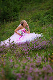 Young beautiful bride sitting at a forest glade