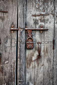 Rusty padlock on an old wooden door of the house