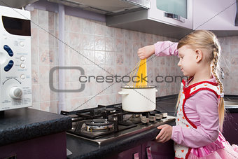 little girl putting pasta in the pot 