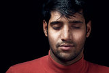 Portrait of young Indian man closed eyes over dark