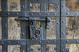 Ancient iron lock with latch on aged boarded door.