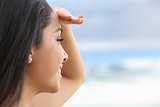 Close up of a beautiful woman looking at the horizon with a hand in forehead