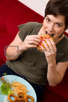Attractive Manicured WOman Bites into Cheeseburger at Lunch Time