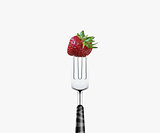 strawberry  pierced by fork,  isolated on white background 