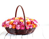 wicker basket with multicolored flowers on wooden table