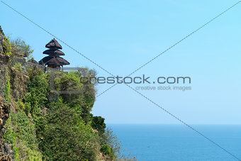 balinese temple on rock above blue tropical sea