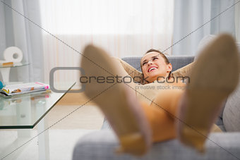 Happy young housewife laying on couch