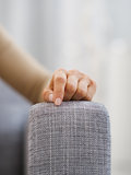 Closeup on hand of stressed woman sitting on couch