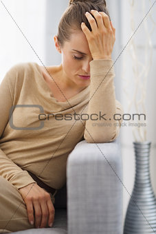 Portrait of stressed young housewife sitting on couch