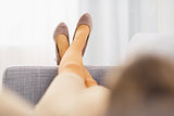 Closeup on leg of young housewife laying on couch