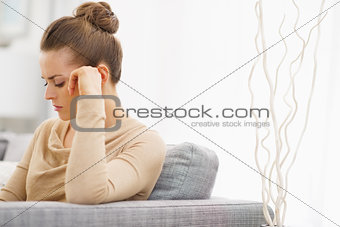 Frustrated young housewife sitting on couch