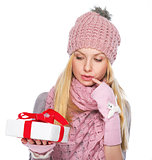 Thoughtful girl in winter clothes looking on christmas present b