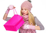 Curious girl in winter clothes looking into christmas shopping b