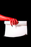 Red devil hand with black nails holding paper scroll 