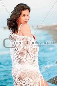 Portrait of a beautiful girl in a white shawl on the beach.