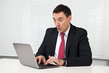shocked young business man looking on his laptop computer