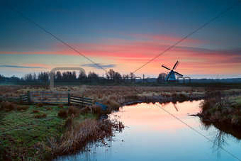 pink sunrise over Dutch windmill and river