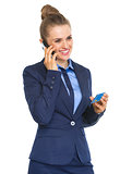 Smiling business woman with credit card talking cell phone