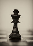 Black wooden chess king on chess board